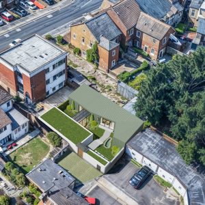 Aerial view of a private villa with brick and metal cladding facades that infills a dismissed parking lot.